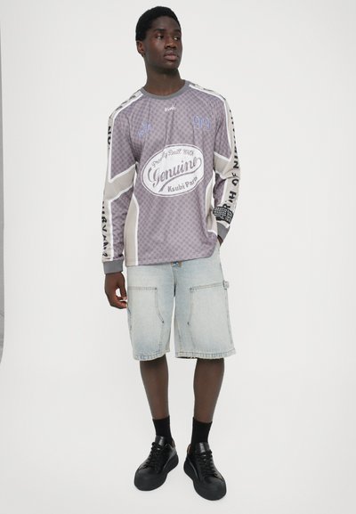 Long-sleeve gray checkered shirt with graphic print, paired with light blue denim shorts featuring front pockets and black sneakers.