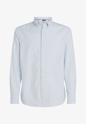 Lys blå stripete skjorte med knapper foran, knappet krage, lange ermer og avrundet kant. Har hvite, smale vertikale striper.