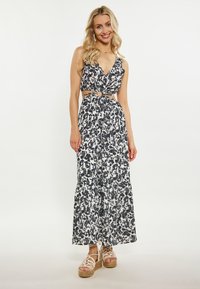 Rochie maxi florală în alb și negru, având un top ajustat cu detalii cu decupaje și o fustă etajată. Asortată cu espadrile cu platformă.