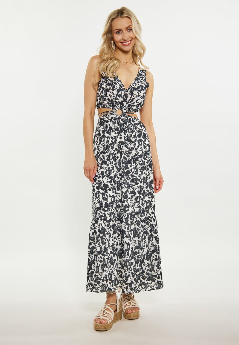 Rochie maxi florală în alb și negru, având un top ajustat cu detalii cu decupaje și o fustă etajată. Asortată cu espadrile cu platformă.