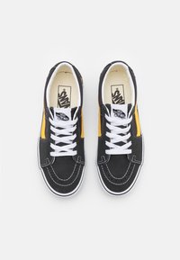 Schwarze Canvas-Sneakers mit weißen Schnürsenkeln, gelben seitlichen Akzenten und weißen Gummisohlen. Verfügen über kontrastierende Nähte und ein Logo auf der Zunge.