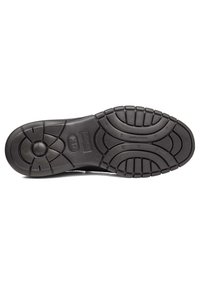 Suela de zapato de goma negra con un patrón de textura para mayor agarre, secciones reforzadas y un logotipo central. Bordes lisos y acentos en relieve.