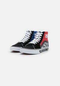 Sneakers înalte au un corp din suede negru, accente roșii și albastre, șireturi albe și un model de zebră pe talpă, cu detalii de branding.