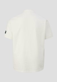 Weißes Poloshirt aus strukturiertem Stoff, mit kurzen Ärmeln und einem klassischen Kragen. Ein kleines Logo am linken Ärmel fügt Details hinzu.