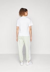 adidas Sportswear ESSENTIALS 3-STRIPES LOOSE-FIT - Tepláky - linen green