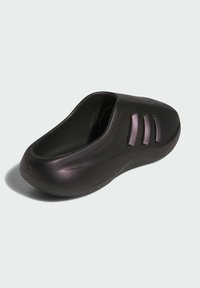 Svarta slip-on clogs med tre ventilationsspringor på sidan och en texturerad sula, visade mot en ljusgrå bakgrund.