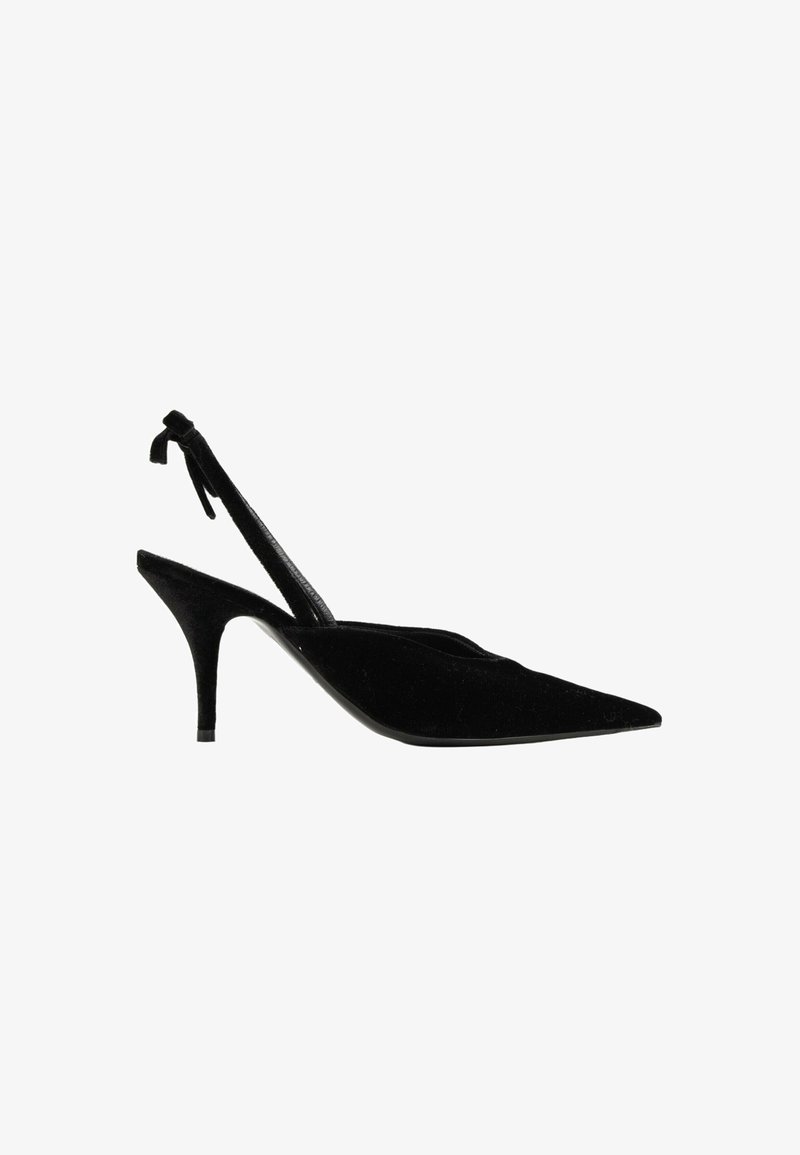 Chaussure slingback à talon haut en daim noir avec bout pointu, talon fin et bride à la cheville sur fond blanc.
