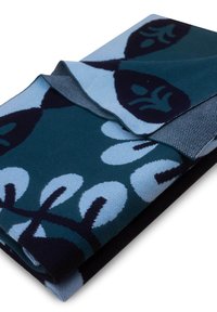 Złożony wełniany koc w kolorze teal, z dużymi ciemnoniebieskimi wzorami kwiatowymi i teksturowaną szarością wzdłuż krawędzi.