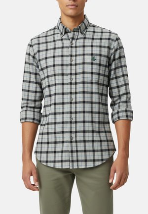 Camisa de franela a cuadros gris y negro con acentos azules, cuello abotonado, mangas largas remangadas hasta los codos y bordado de logo en el pecho.