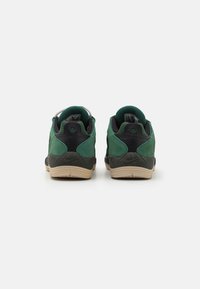 Green and black suede sneakers with a textured finish, featuring a beige rubber sole and prominent Nike branding on the heel.