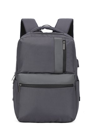 Un sac à dos gris avec des bretelles rembourrées, plusieurs compartiments zippés et une poignée de transport en haut sur un fond blanc.