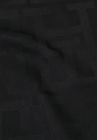 Tissu noir texturé avec un motif subtil de formes géométriques entrelacées, présentant une surface lisse et une coloration sombre uniforme.