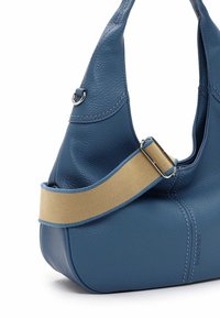 Borsa in pelle blu con finitura testurizzata, dotata di una tracolla in tessuto beige, base arrotondata e sottili dettagli di cucitura.