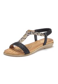 Schwarze geflochtene Sandale mit einem geflochtenen, metallischen Riemen, gepolstertem, tanfarbenem Fußbett und einer flexiblen, hellen Sohle. Verstellbarer elastischer Hinterriemen.