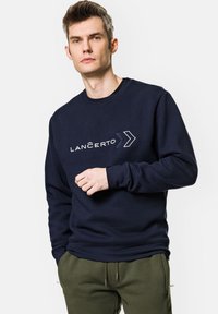 Granatowy sweatshirt z okrągłym dekoltem, z białym haftowanym napisem "LANCERTO" i wzorem strzały. Miękka tkanina i luźny krój.