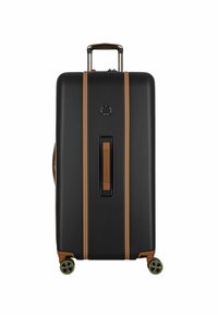 Valise rigide noire avec des accents beiges, texture lisse, poignée extensible et quatre roues. Poignée centrale et détail de logo circulaire.