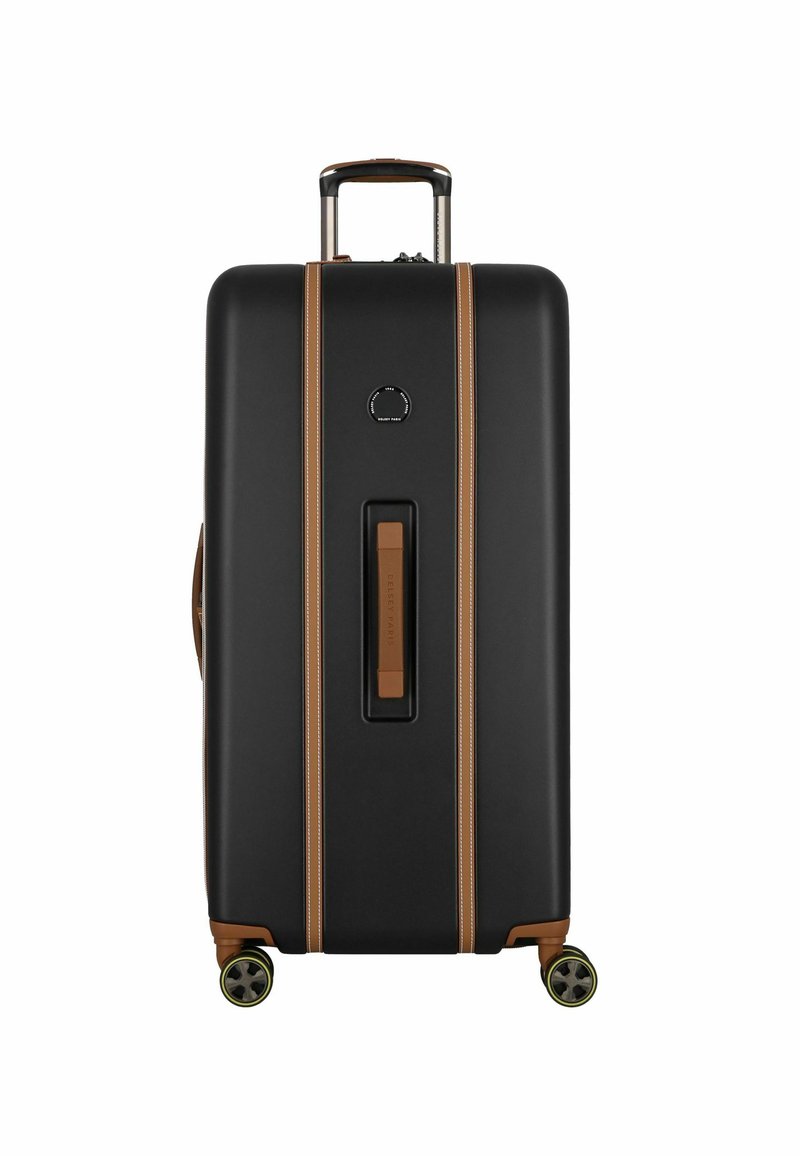 Valise rigide noire avec des accents beiges, texture lisse, poignée extensible et quatre roues. Poignée centrale et détail de logo circulaire.