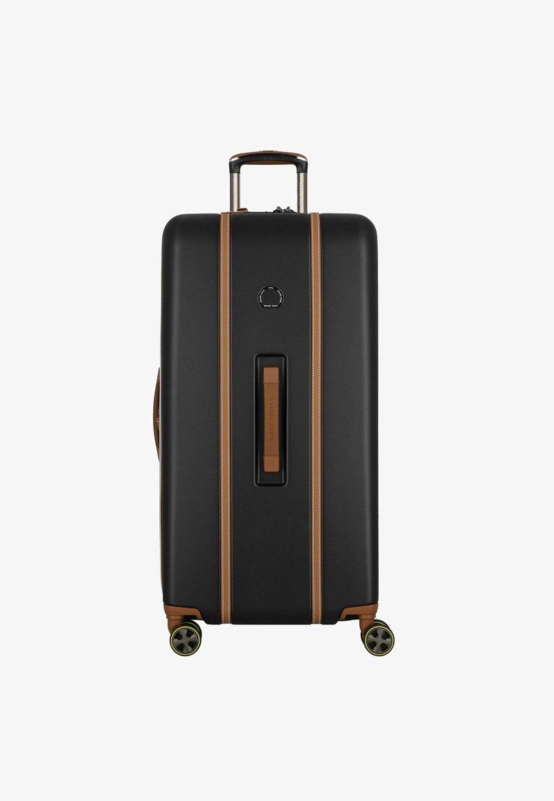 Valise rigide noire avec des accents beiges, texture lisse, poignée extensible et quatre roues. Poignée centrale et détail de logo circulaire.