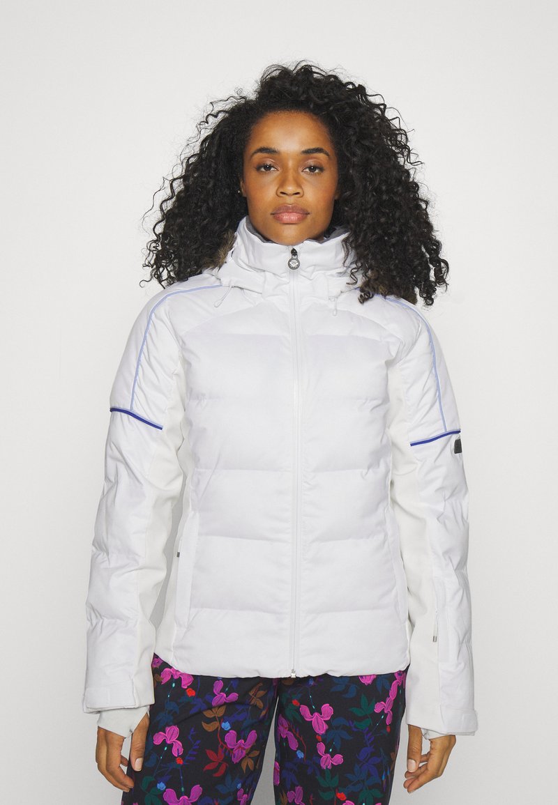 Weißer isolierter Jacke mit hohem Kragen, Reißverschluss und blauen Akzenten, kombiniert mit floral gemusterten Hosen.