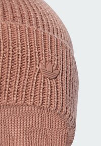 Knit beanie in soft pink with a ribbed texture, featuring a small brown three-leaf logo accent on the side.
