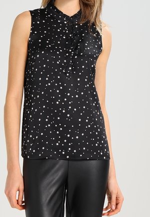 Top senza maniche nero realizzato in tessuto liscio, con motivo a stelle in argento, colletto arricciato e scollatura alta. Abbinato a pantaloni neri.