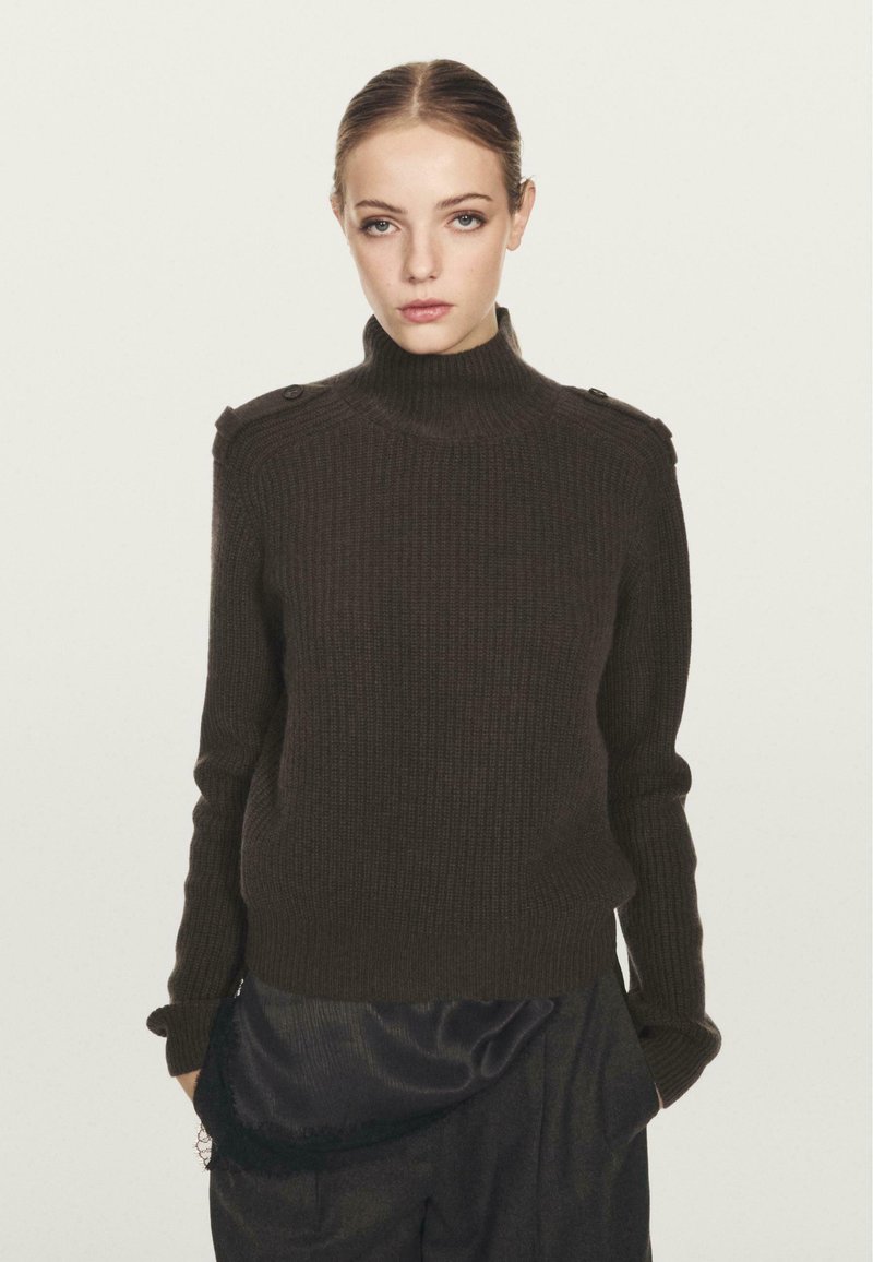 Maglione marrone a coste con collo alto, dotato di bottoni sulle spalle e maniche lunghe. Il design ha una vestibilità rilassata e un tessuto testurizzato.