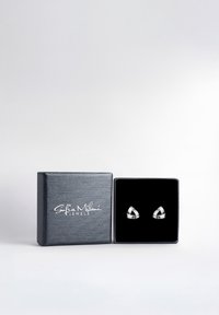 Silver geometriska stiftörhängen visade i en svart sammetslåda med en texturerad grå utsida som har varumärket.