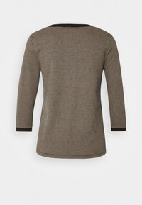 Camiseta de manga larga en un patrón de espiga negro y beige con un escote redondeado y ribetes en negro sólido en los puños. Tejido texturizado y tejido.