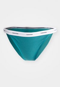 Teal ribbet bomullsbrief med hvit elastisk midjebånd som har "Calvin Klein" branding. Klassisk form med en glatt tekstur.