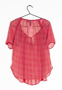 Blusa a maniche corte rossa con motivo, realizzata in un tessuto leggero e trasparente, caratterizzata da un collo rotondo e un dettaglio a fiocco sul retro.