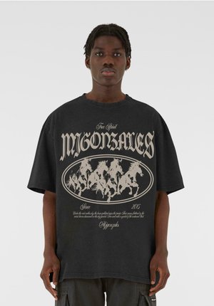 Black oversized t-shirt featuring a central graphic of galloping horses in gray with decorative text above and below, made of cotton material.