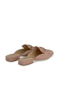 Mules en daim rose avec une semelle plate, un dos ouvert et des éléments décoratifs sur le devant, présentant une texture lisse et un design minimaliste.