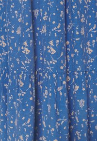 Blått tyg med en texturerad yta, med ett blommönster i ljusa nyanser. Designen inkluderar olika små blommor och bladverk.