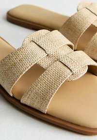 Sandali piatti in beige chiaro con cinturini in tessuto intrecciato, soletta sintetica liscia e suola in gomma a profilo basso.