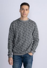 Pulover cu un model geometric în crem și bleumarin, gât rotund, manșete și tiv striate, realizat dintr-un material moale.