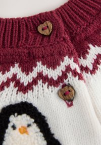 Pull tricoté rouge et blanc orné d'un motif pingouin, avec un col côtelé et des boutons en forme de cœur en bois.