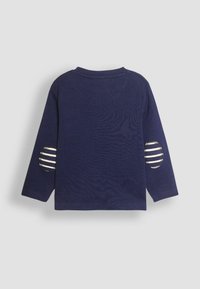 Marinblus med lång ärm, rund halsringning och randiga tygaccenter på armbågsflickor för extra textur. Mjuk bomullsmaterial.