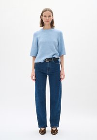 Ljust blå, kortärmad stickad tröja i kombination med högmidjade, rakbenade mörkblå jeans och lägenheter med leopardmönster. Svart bälte för accent.