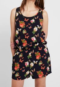 Mono corto negro con flores que presenta un diseño sin mangas, vibrantes patrones de flores y mariposas, cintura elástica y tejido ligero.