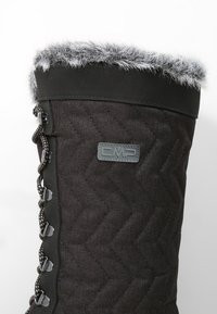 Zwarte gequiltte stoffen laars met nepbontafwerking, gekenmerkt door een gestructureerd oppervlak, vetersluiting details en een CMP-logo patch aan de zijkant.