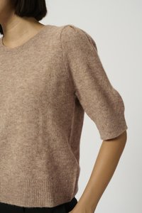 Lys rosa strikket sweater med rund halsudskæring, korte puffærmer og ribbet kant. Stoffet ser blødt ud med en fuzzy tekstur.