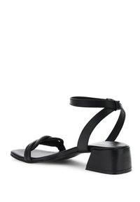 Sandal in pelle nera con design della fascia attorcigliata, cinturino alla caviglia con fibbia e tacco basso per stabilità.