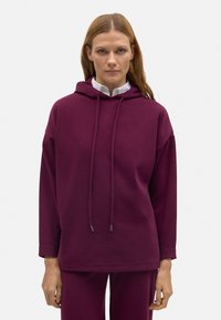 Sudadera con capucha de color burdeos, de corte holgado, con mangas largas y cordones, fabricada en una tela suave. Presenta puños y dobladillo acanalados.