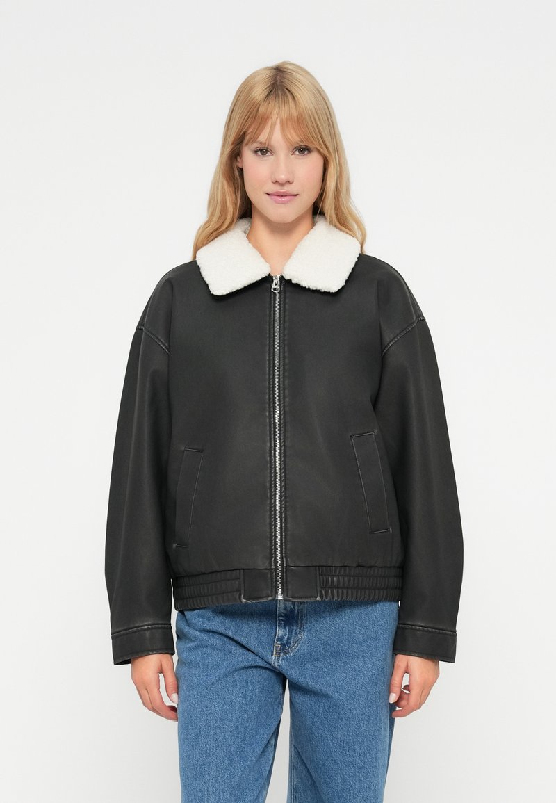 Μαύρο τεχνητό δερμάτινο μπουφάν με λευκό πλεκτό γιακά, μπροστινό φερμουάρ, πλαϊνές τσέπες και ribbed στρίφωμα; χαλαρή εφαρμογή με πτώση στους ώμους.