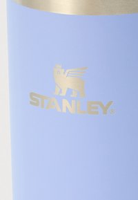 Borraccia Stanley in blu chiaro opaco con coperchio in metallo spazzolato, con logo dorato di un leone coronato con ali e testo in rilievo.