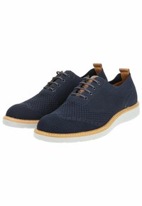 Scarpe in maglia blu navy con superficie testurizzata, dettagli in pelle beige e suola in gomma bianca. Presenta sei occhielli per i lacci.