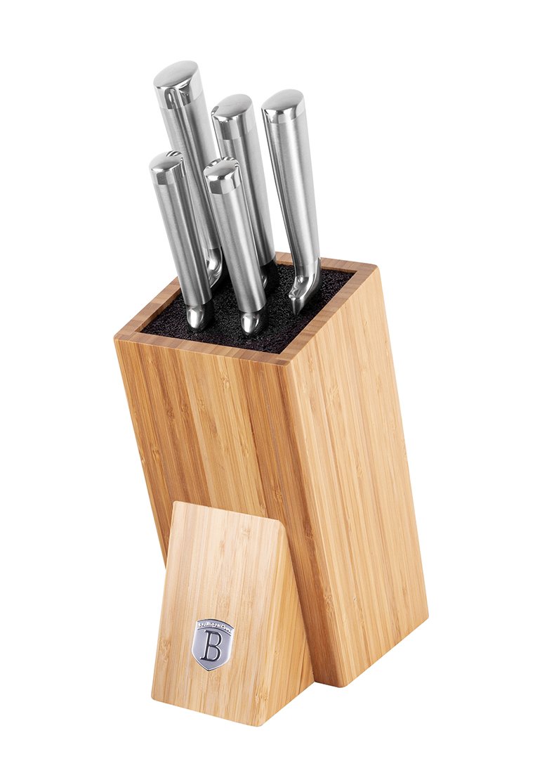 Bamboo block na noże trzymający pięć noży ze stali nierdzewnej z zaokrąglonymi uchwytami, nachylony w prawo na białym tle.