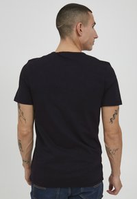 Black short-sleeve t-shirt made of soft cotton. Features a classic crew neckline and a smooth texture, with minimal detailing.