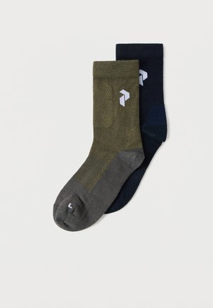 Paire de chaussettes montantes, une vert olive avec bordure et talon gris, et une bleu marine foncé, toutes deux avec un logo géométrique blanc près du bord côte.