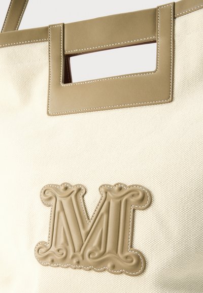 Τσάντα ώμου από κρεμ ύφασμα με τετράγωνη λαβή από ταμπά δέρμα και ανάγλυφο ραμμένο γράμμα "Μ" στο μπροστινό μέρος.